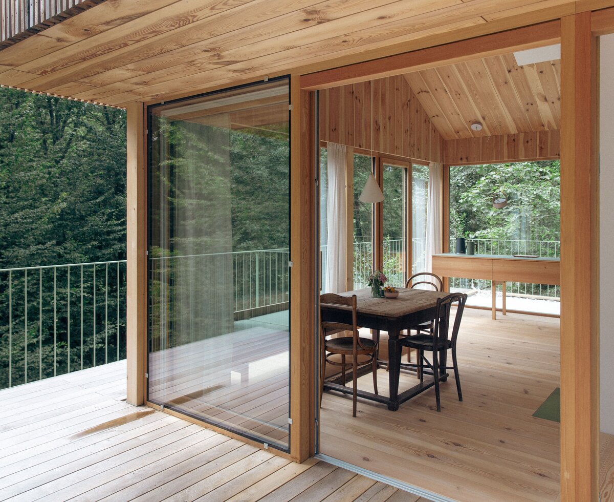 Urlaub zwischen den Baumwipfeln im Baumhaus Buchengrün in der Steiermark | © Urlaub am Bauernhof / Margit Terpotitz Blick von der Terrasse des Baumhauses aus Holz in den rundum verglasten Wohnraum und auf die Baumwipfel | © Urlaub am Bauernhof / Margit Terpotitz