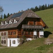 Ferienhaus, gebaut aus Stein und Holz, im Hintergrund eine grüne Wiese und der Waldrand | © Staberhof / Familie Pieber