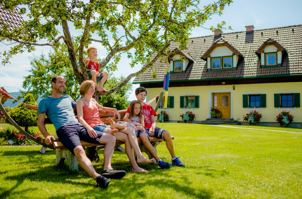 Familie mit Kindern sitzt auf einer Holzbank vor dem Bauernhof | © Urlaub am Bauernhof Steiermark / Wolfgang Spekner