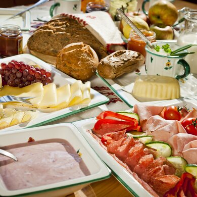 Üppig gedeckter Frühstückstisch mit Wurst, Käse, Butter, Brot, Milch, Aufstrichen | © Urlaub am Bauernhof Steiermark / Werner Krug