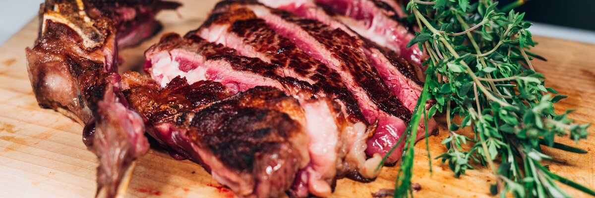 aufgeschnittenes Steak mit Kräutern auf Holz, Hochsteiermark, Steiermark | © Urlaub am Bauernhof / Daniel Gollner
