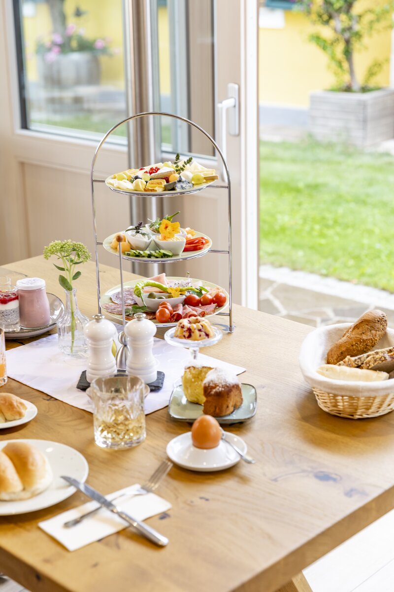 Frühstückstisch mit Wurst, Käse und Gemüse, dekorativ in einer Etagere serviert, mit einem weichen Eier, Brotkörbchen, Minigugelhupf, Buchtel und Joghurt.  | © Urlaub am Winzerhof / Elisabeth Fröhlich