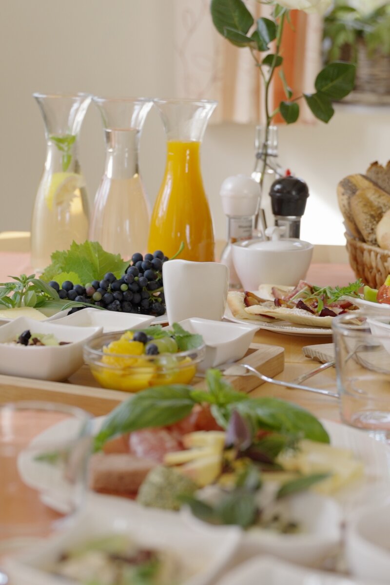 Liebevoll gedeckter Frühstückstisch mit Aufstrichen, Marmelade, Honig und Früchten in kleinen Schälchen, im Hintergrund stehen Karaffen mit Wasser und Orangensaft und ein Gebäckkorb | © Urlaub am Bauernhof / Daniel Gollner