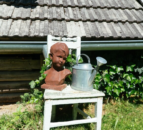 Tonkopf eines Kindes und alte gusseiserne Gießkanne als Dekoration im Garten, Biobauernhof Leitenmüller, Steiermark | © Urlaub am Bauernhof Steiermark / Daniel Gollner