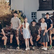 Familienfoto mit 4 Männern und 2 Frauen, aufgenommen vor einem Holzstoß | © Kainreiter / Familie Pitzer