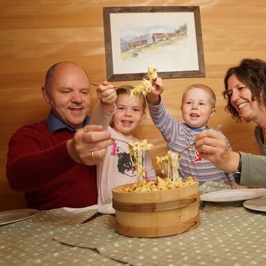 Familie beim Käsknöpfe essen am Tisch | © Urlaub am Bauernhof Vorarlberg / Ludwig Berchtold
