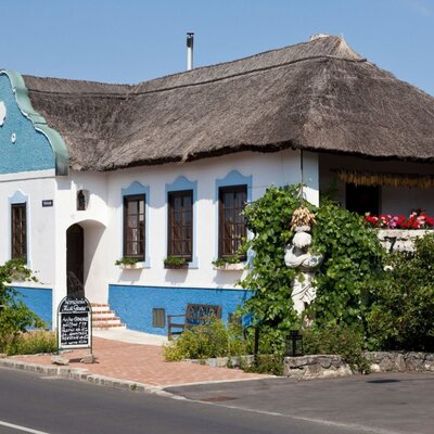 Das charmante Bed and Breakfast mit traditionellem Reetdach, einer charakteristischen blau-weißen Fassade und üppigem Grün.