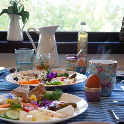 Ein liebevoll angerichtetes, frisches Bio-Frühstück im Bed and Breakfast mit einer bunten Auswahl an Aufstrichen, gekochten Eiern und warmen Getränken.