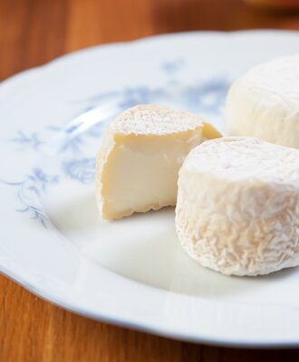 Eine Auswahl an feinem, cremigem Weichkäse auf einem hübschen Teller zum Frühstück im Bed and Breakfast.