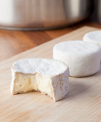 Frischer, cremiger Weichkäse auf einem Holzbrett als Teil des kulinarischen Angebots im Bed and Breakfast.