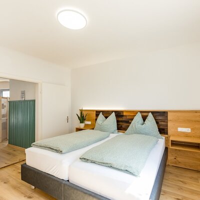 Schlafzimmer im Bed and Breakfast mit Doppelbett, Holzkopfteil und Zugang zum angrenzenden Badezimmer.