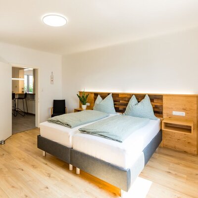 Schlafzimmer im Bed and Breakfast mit zwei Einzelbetten, Holz-Kopfteil mit Beleuchtung und Zugang zu einem angrenzenden Raum.