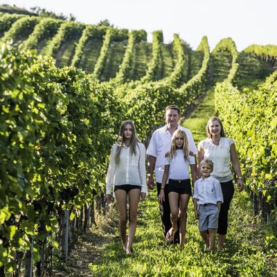 Eine Familie spaziert durch die Weinberge des Hofes.