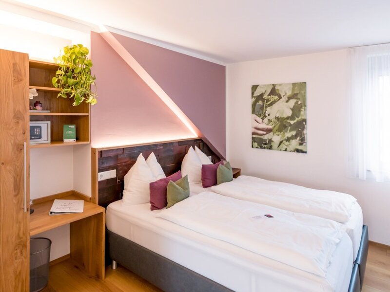 Schlafzimmer im Hof mit Doppelbett, Holzschreibtisch, Regal, Safe und Holzboden.