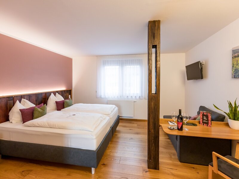 Gästezimmer im Hof mit zwei Einzelbetten, einem kleinen Sitzbereich und einem Fernseher.