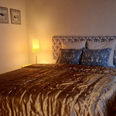 Das Schlafzimmer im Hof bietet ein Doppelbett mit Kopfbrett, zwei Nachttischlampen und Wandbilder mit Tiermotiven.