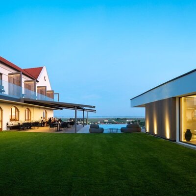 Der Außenbereichmit Terrasse, Infinity-Pool, Rasenfläche und dem modernen Wellnessbereich.