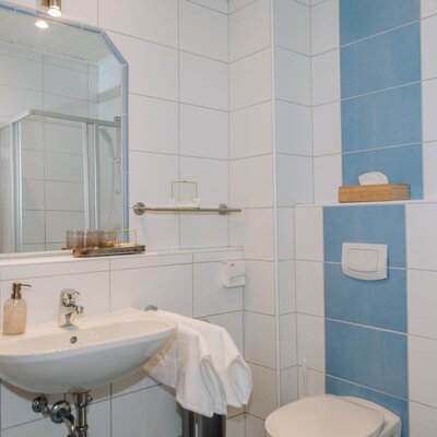 Badezimmer im Haus mit Waschbecken, Spiegel, Toilette und Dusche.