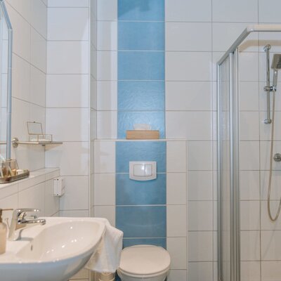Badezimmer im Haus mit Waschbecken, Spiegel, Toilette und Duschkabine.