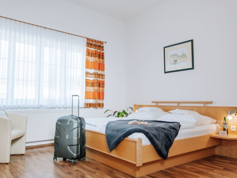 Schlafzimmer im Haus mit Doppelbett, Nachttisch, Leselampe, Sessel und Fenster.