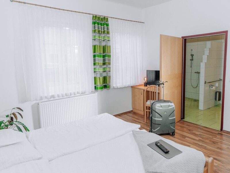 Schlafzimmer im Haus mit Bett, Fenster, Schreibtisch mit Kabel-TV und Zugang zum Badezimmer.