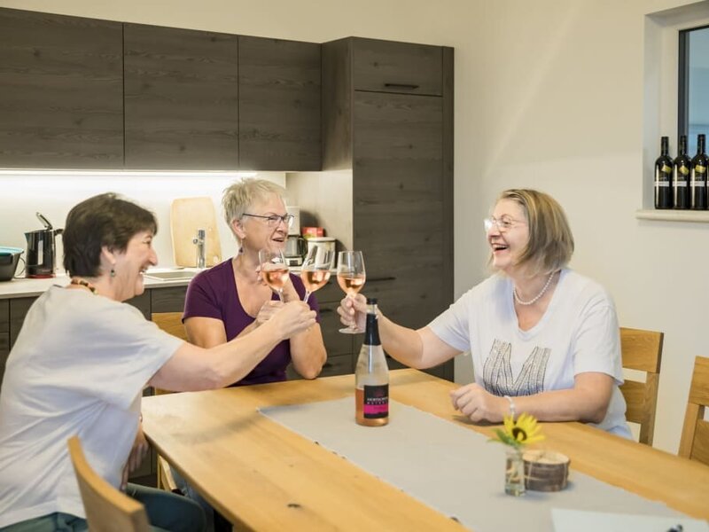 Die Genuss- und Plauderstube mit Küchenzeile, in dem Gäste gemeinsam bei einem Glas Wein zusammenkommen.