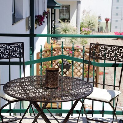 Balkon am Hof mit einem runden Metalltisch und zwei passenden Stühlen.