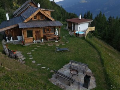 Die einladende Alm mit einem gepflegten Garten, einer gemütlichen Grillecke und einem beheizten Außenpool inmitten einer malerischen Berglandschaft.