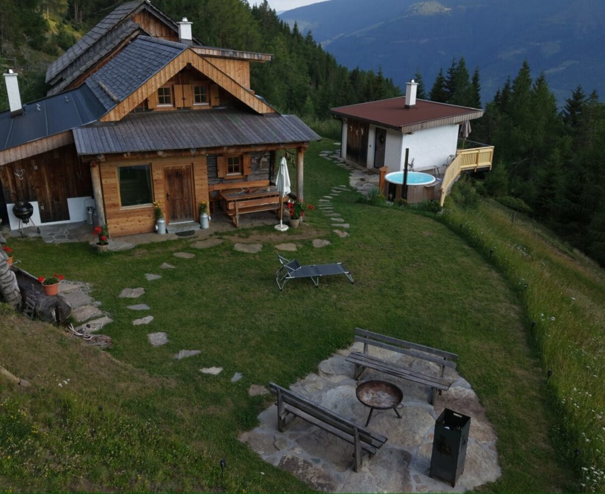 Die einladende Alm mit einem gepflegten Garten, einer gemütlichen Grillecke und einem beheizten Außenpool inmitten einer malerischen Berglandschaft.