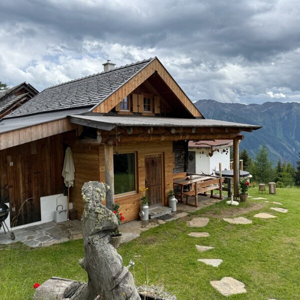 Urige Alm mit einer gemütlichen Holzterrasse, Grillplatz und weitem Blick auf die umliegenden Berge.
