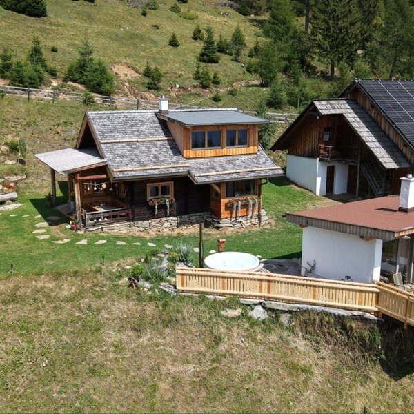 Gesamtansicht des Almchalets Kampleck mit privatem Saunahaus, Hot Tub und Terrasse – eingebettet in die ruhige Natur der Alm.