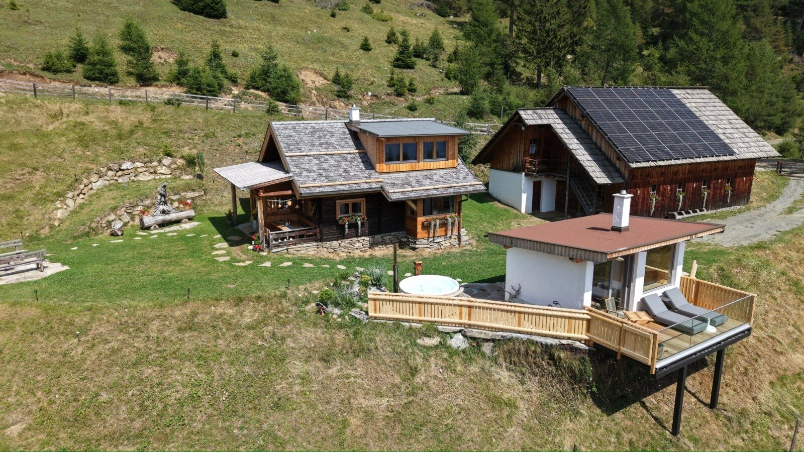 Gesamtansicht des Almchalets Kampleck mit privatem Saunahaus, Hot Tub und Terrasse – eingebettet in die ruhige Natur der Alm.
