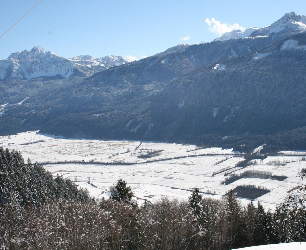 Blick auf das verschneite Tal und die umliegenden Berge.