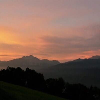 Blick auf die Berglandschaft mit farbenfrohem Himmel von der Alm.