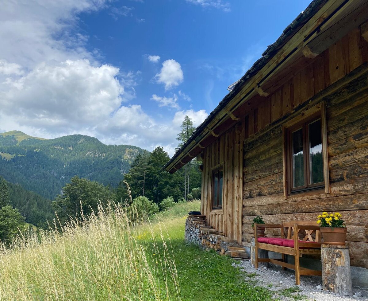 Außenansicht des Bed and Breakfast in Holzbauweise mit einer Sitzbank und Blick auf die Berge.