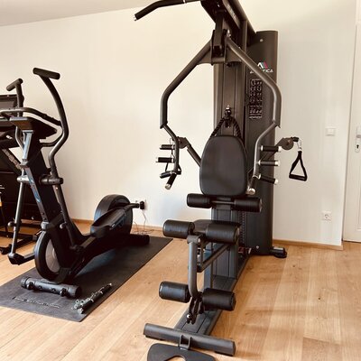 Fitnessraum im Ferienhaus mit Kraftstation und Crosstrainer.