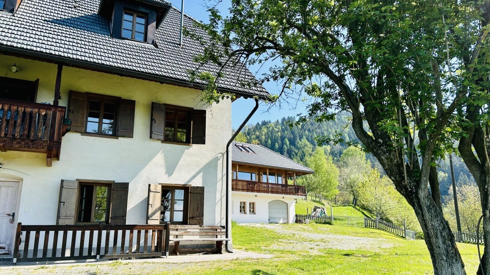 Das Ferienhaus mit Balkon, Holzfensterläden und einer Rasenfläche mit Bergblick.