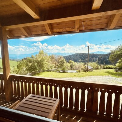 Balkon des Ferienhauses mit Holztisch und weitem Blick auf die hügelige Landschaft.