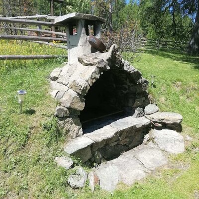 Der gemauerte Stein-Grill im Gartenbereich der Alm, ideal für Mahlzeiten im Freien.