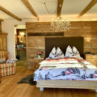 Großzügiges, urig-luxuriöses Schlafzimmer im Chalet mit Doppelbett und Zugang zum Bad en Suite