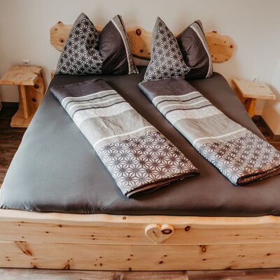 Doppelzimmer im Bauernhof mit Zirbenvollholzmöbeln und einem Doppelbett.