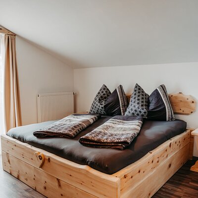 Schlafzimmer des Appartements auf dem Bauernhof mit Doppelbett aus Zirbenvollholz.