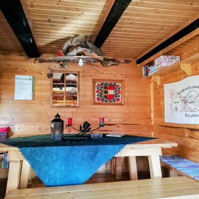 Essbereich der Alm mit Holztisch, Holzbänken und traditioneller Dekoration.