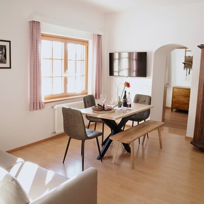 Essbereich im Familienappartement des Bauernhofs mit Esstisch, Stühlen, Bank, Sofa und Fernseher.