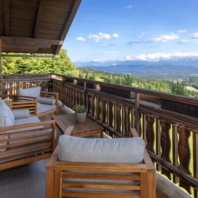 Terrasse des Ferienhauses mit Holzmöbeln und weitem Blick auf die Berge und das Tal.