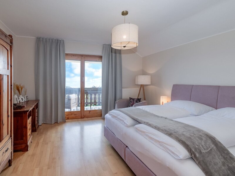 Schlafzimmer im Bauernhof mit Doppelbett, Holzschrank und Zugang zum Balkon.