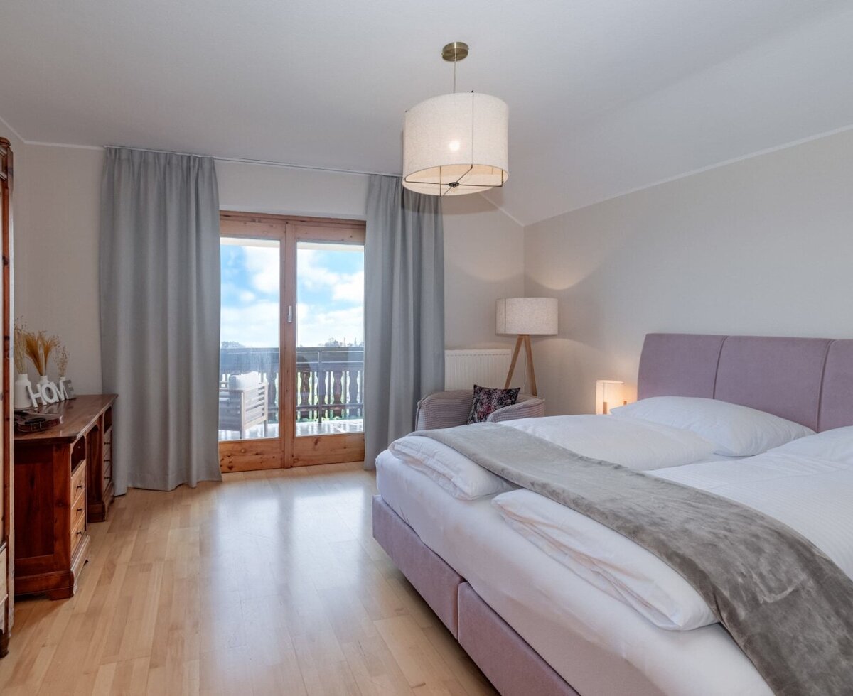 Schlafzimmer im Bauernhof mit Doppelbett, Holzschrank und Zugang zum Balkon.