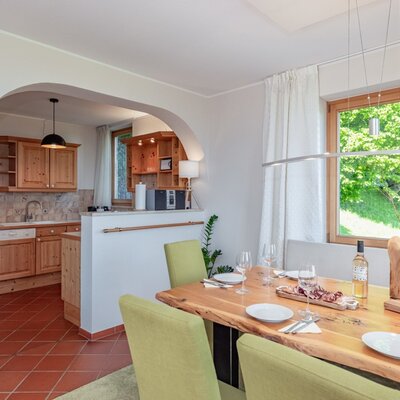 Der große Esstisch im Bauernhof, gedeckt für eine Mahlzeit, mit Blick auf die voll ausgestattete Küche.