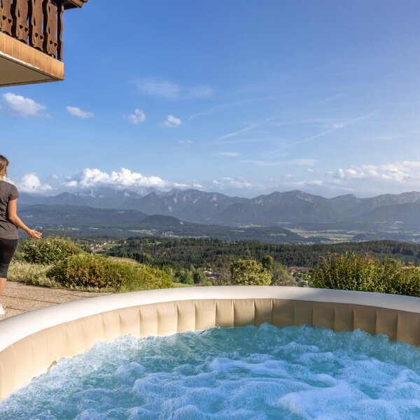 Der Whirlpool und die Außendusche auf der Terrasse des Bauernhofs mit weitem Blick über die Berge und das Tal.