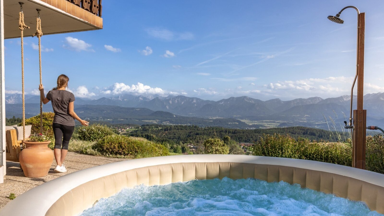 Der Whirlpool und die Außendusche auf der Terrasse des Bauernhofs mit weitem Blick über die Berge und das Tal.